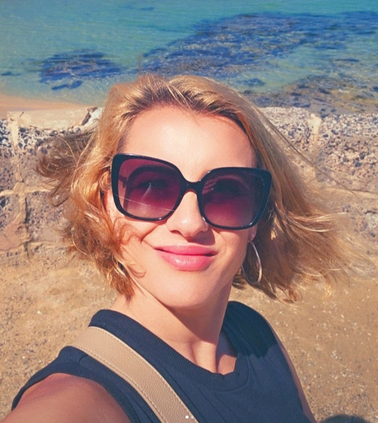 Rafaela Lambrou, Melbourne-based artist and founder of Art by Rafaela, photographed at the beach in Greece — her greatest source of inspiration