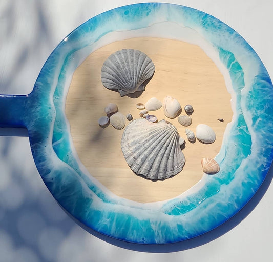 Hand-poured resin round serving platter by Art by Rafaela with vivid turquoise ocean waves surrounding a natural hardwood centre